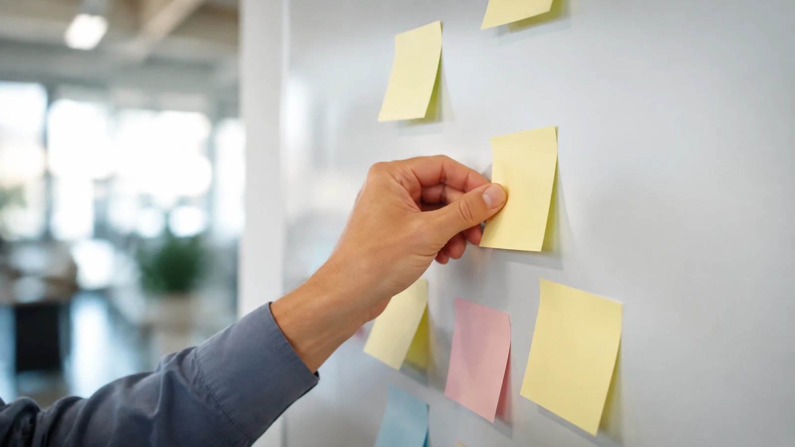 Main posant une note sur un support mural